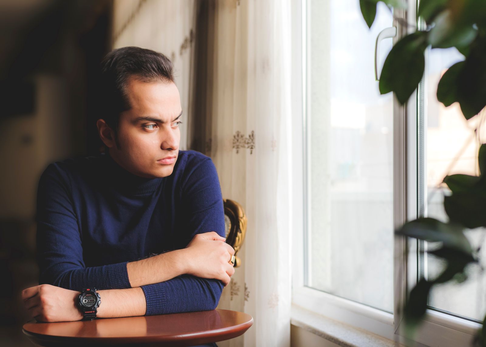 Person sitting quietly in reflection, looking out of a sunlit window