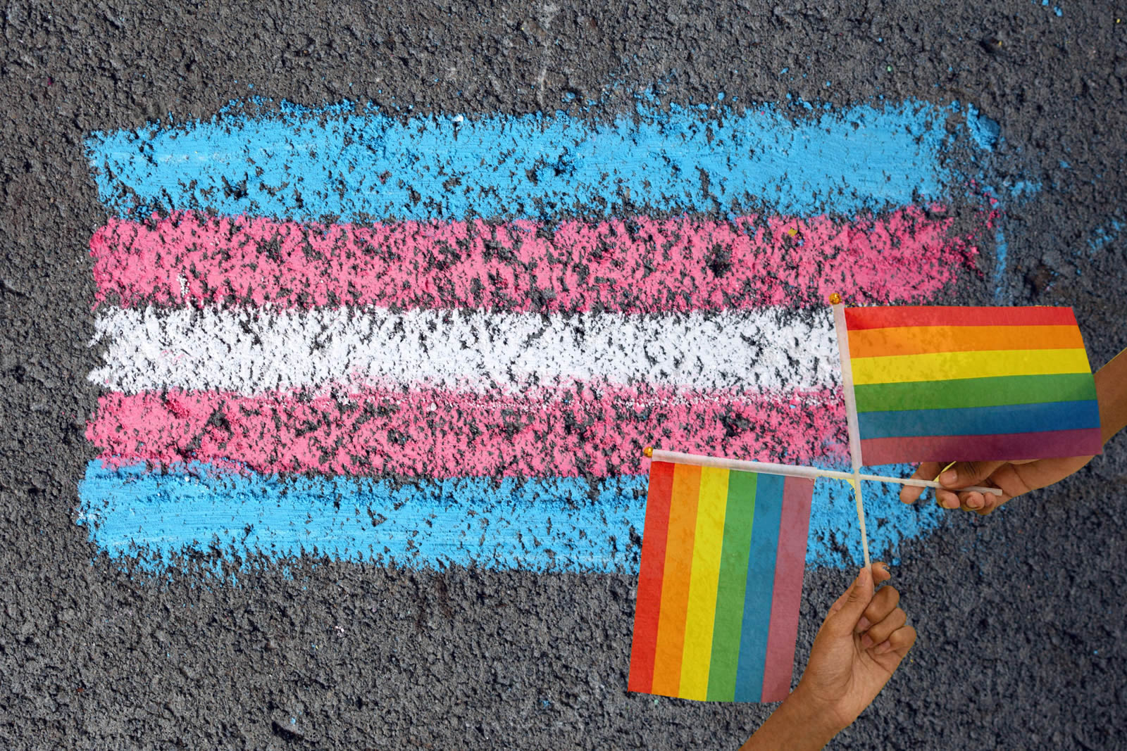 Two people crossing rainbow pride flags together